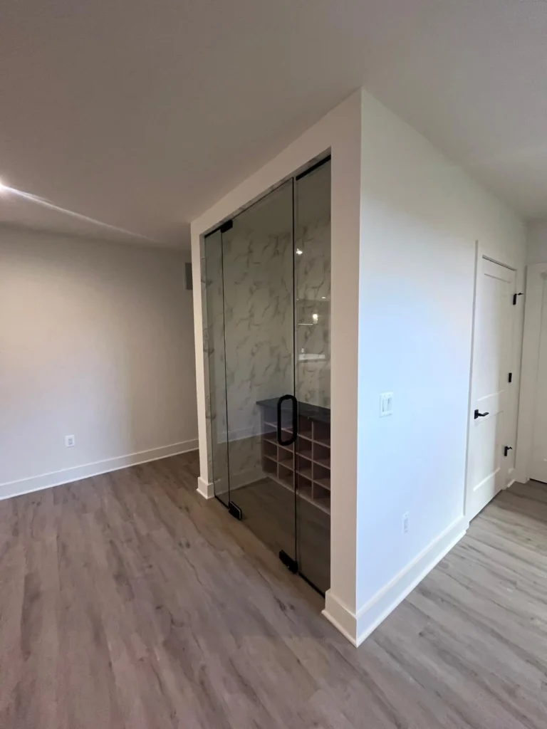A modern home hallway with spotless wood floors and a streak-free glass-enclosed wine display, showcasing detailed residential cleaning by L&V Cleaning.