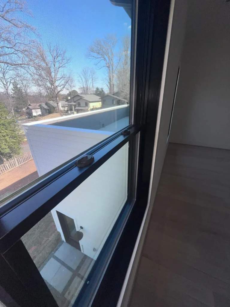 An open, black-framed window looking out over a neighborhood, featuring perfectly wiped, dust-free glass and sills after a detailed clean by L&V Cleaning.