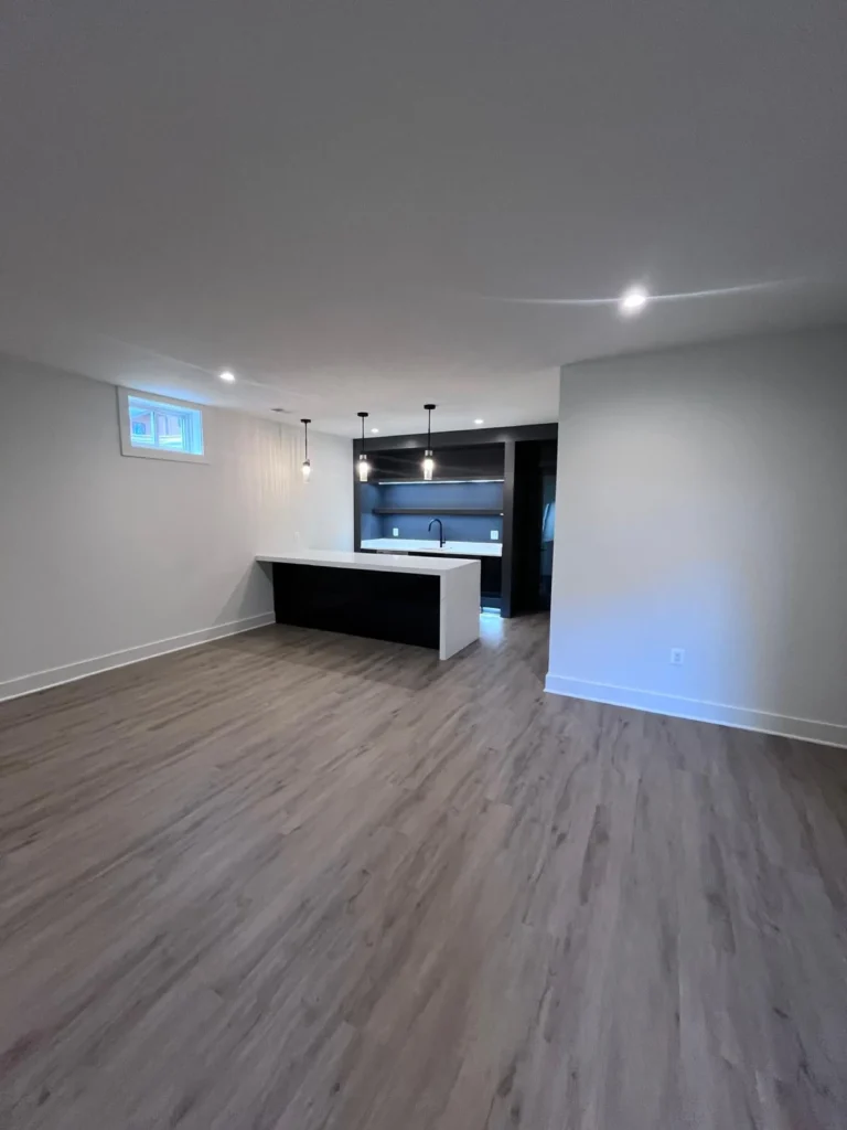 "A spacious, newly finished basement with spotless wood-look floors leading to a modern dark-toned wet bar, cleaned by L&V Cleaning.