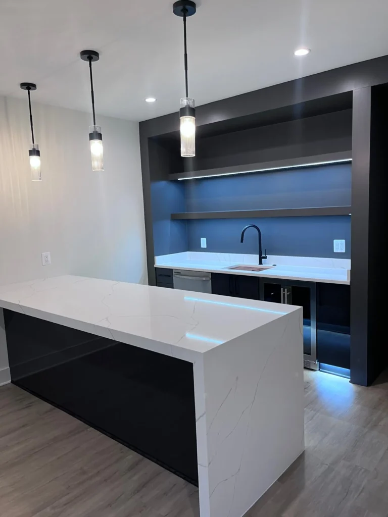 A pristine modern basement bar area featuring a gleaming white quartz waterfall countertop, dust-free dark shelving, and polished pendant lights after a deep clean by L&V Cleaning.