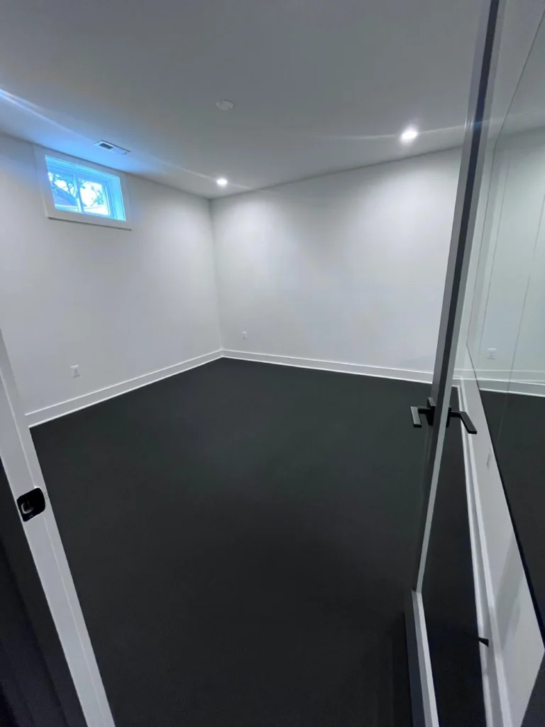 An empty, immaculate home gym or office space with freshly cleaned dark flooring, bright white walls, and a streak-free glass door, maintained by L&V Cleaning.