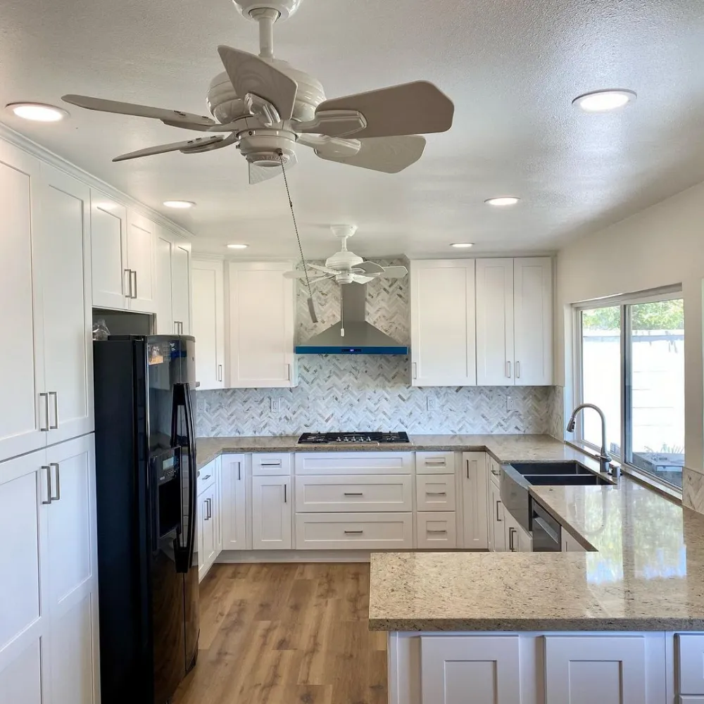 A bright, modern kitchen featuring white shaker cabinets and granite countertops, left spotless after a professional cleaning by L&V Cleaning.