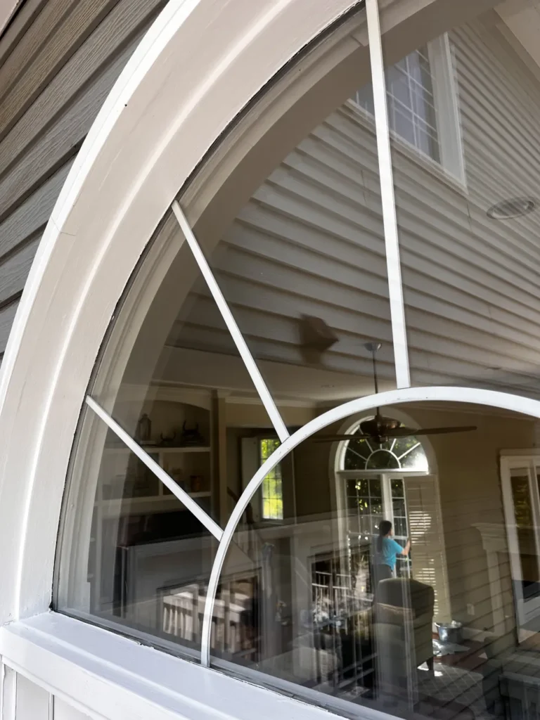 Exterior view of a large arched window with streak-free glass and clean white trim, reflecting interior cleaning work by L&V Cleaning.