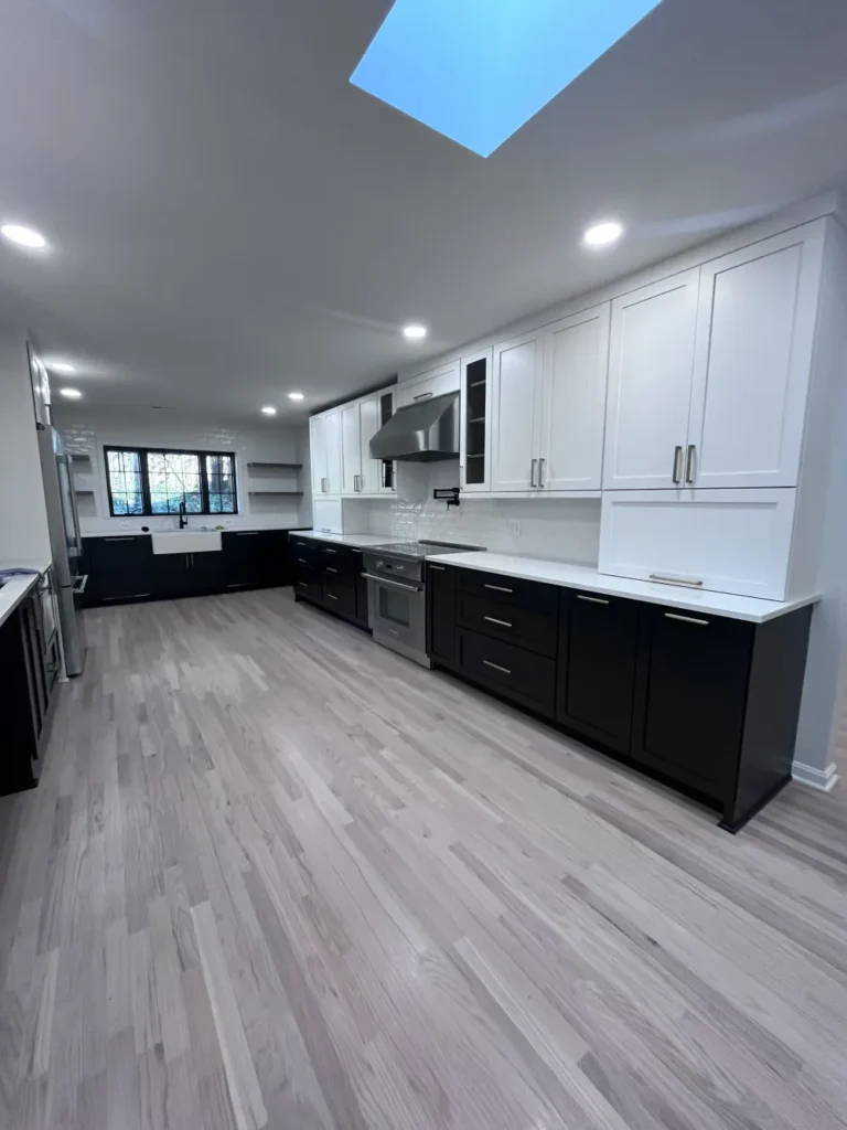 A spacious kitchen with dust-free black and white cabinets and shining stainless steel appliances after a detailed clean by L&V Cleaning.
